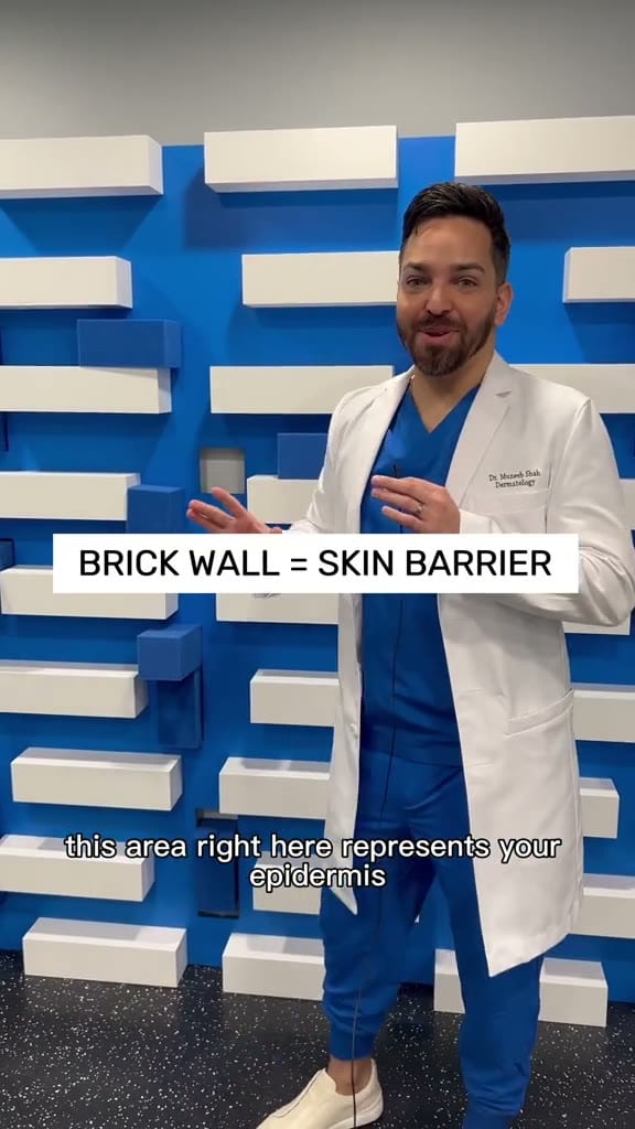 Get Noticed, On-screen caption 'BRICK WALL = SKIN BARRIER' locks the metaphor early, but the brand mark hasn't landed yet.