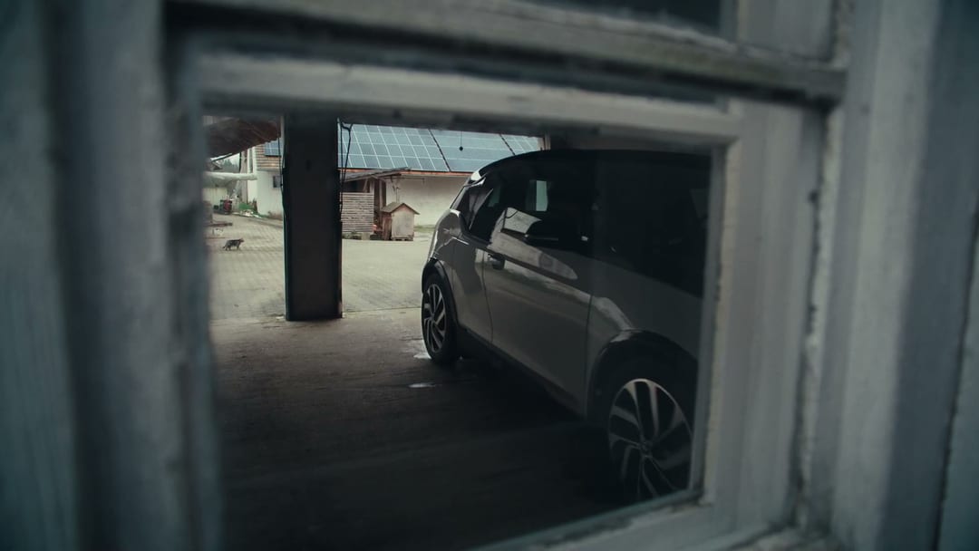 Sell Proposition, BMW i3 parked in the courtyard of the same farmstead, narrative arrives at destination, plug-in moment imminent.