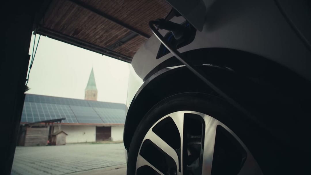 Build Brand, Charging plug close-up against the wheel + church spire, the proof point of the electric story.